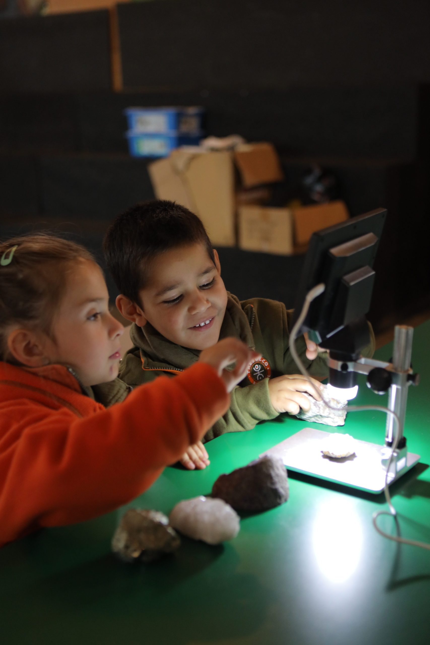 Niños observando una roca con un microscopio digital en una estación de Astro Ruta